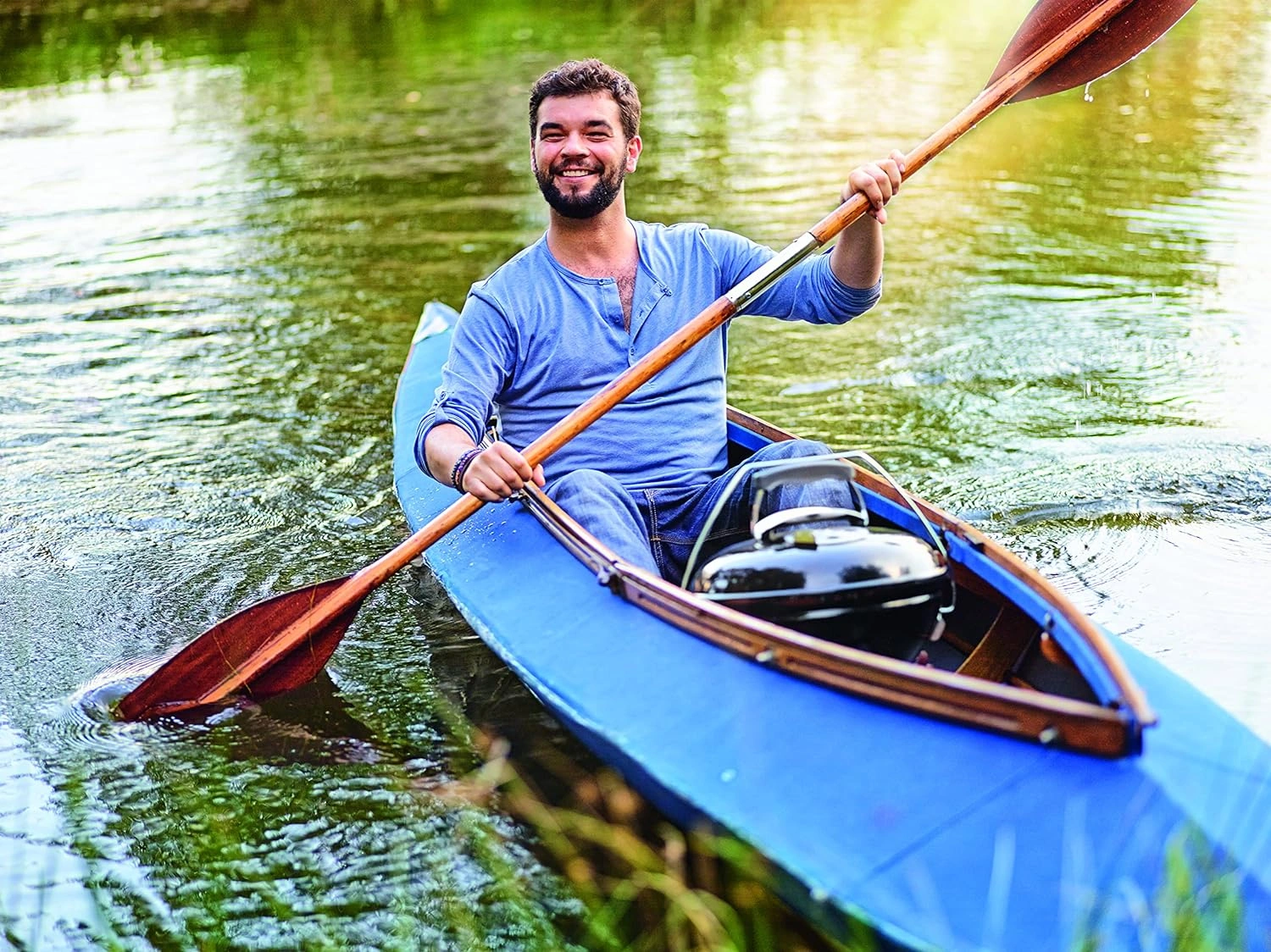 Barbat in canoe pe apa cu un gratar Smokey Joe pe carbuni in barca